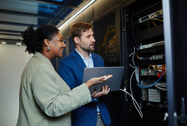Two people performing a network audit in a business to ensure the infrastructure is still working as it should.